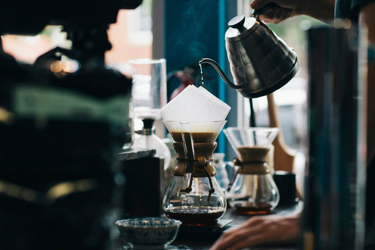 Pouring hot water over coffee grounds in a pour-over brewer