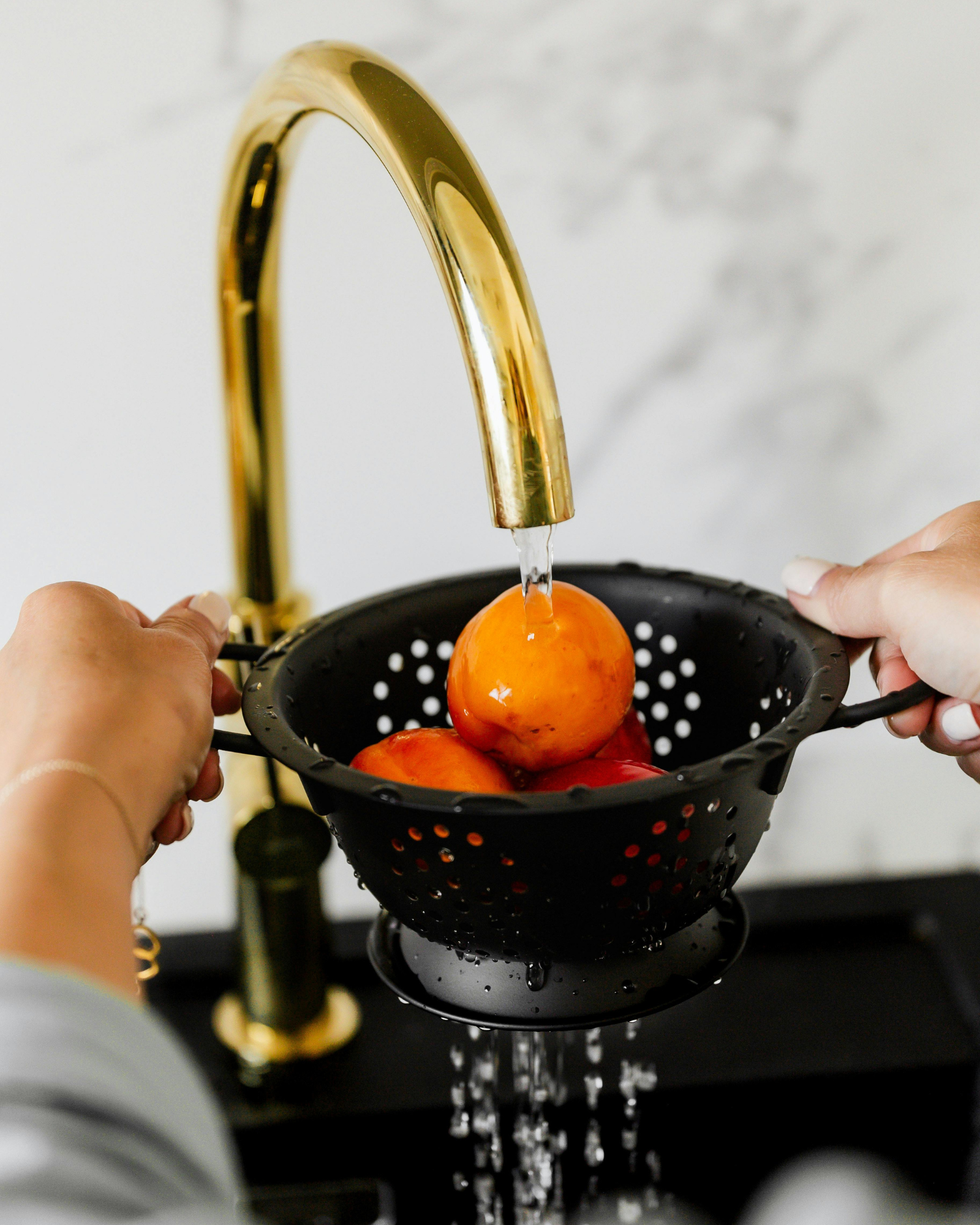 Washing fresh fruit with filtered tap water in a kitchen, illustrating everyday household water filtration use in Europe