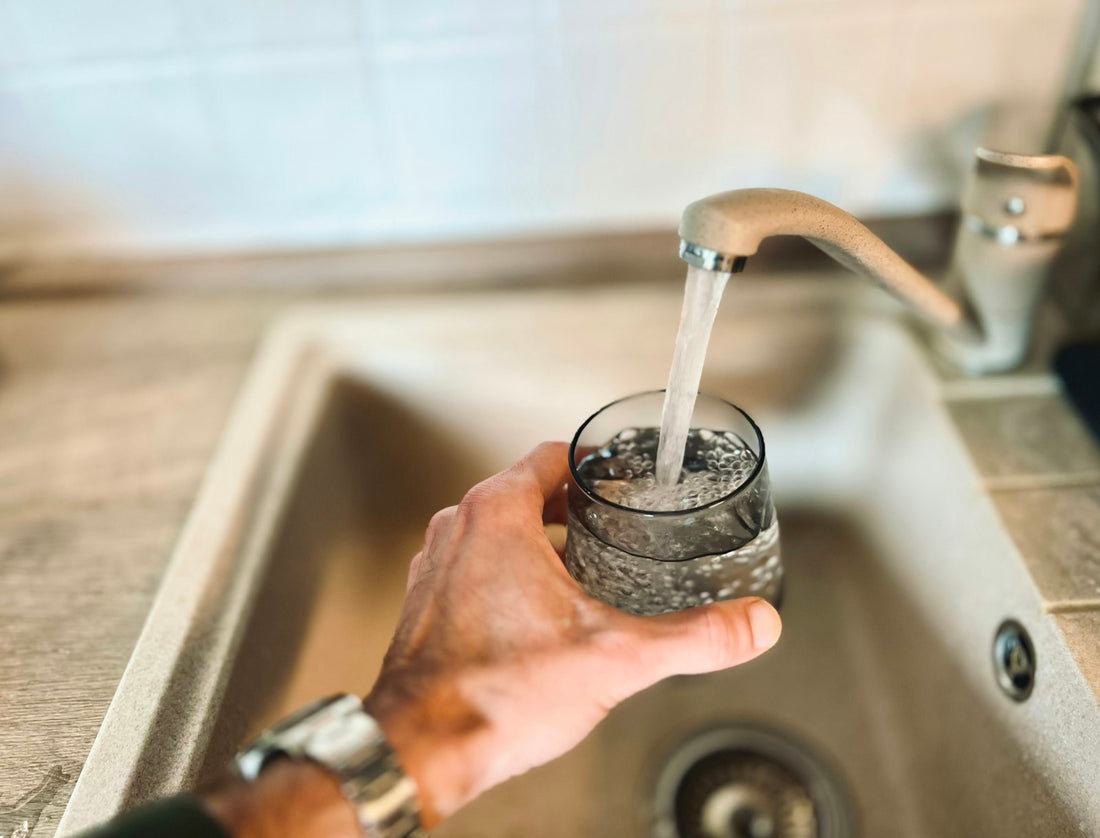Hand filling a glass of water from a kitchen tap, representing everyday UK tap water use