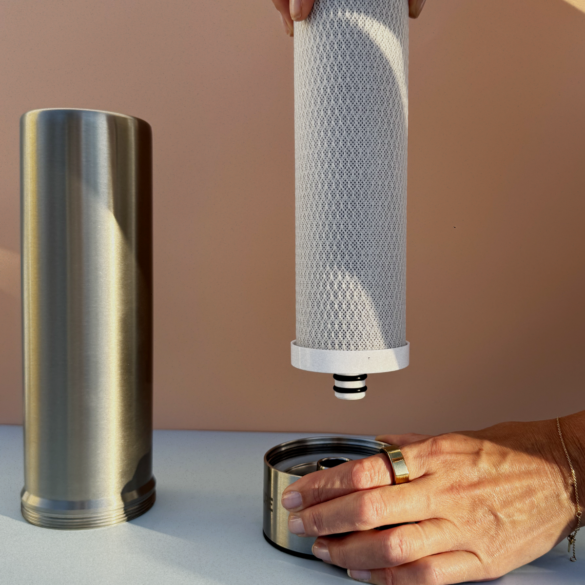 Person replacing a Pjure water filter  with a beige background