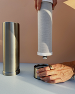 Person replacing a Pjure water filter  with a beige background