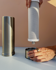 Person replacing a Pjure water filter  with a beige background