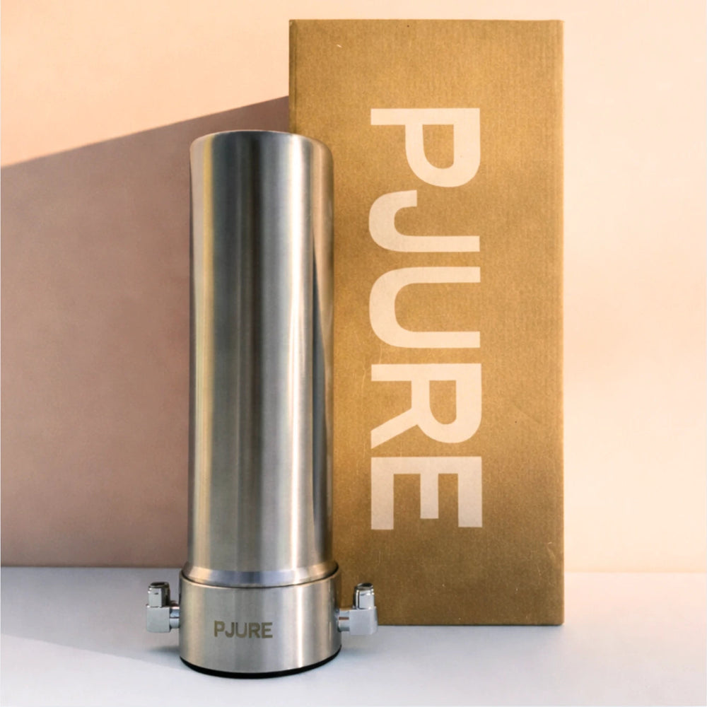 PJURE stainless steel under-sink water filter standing next to its kraft cardboard box