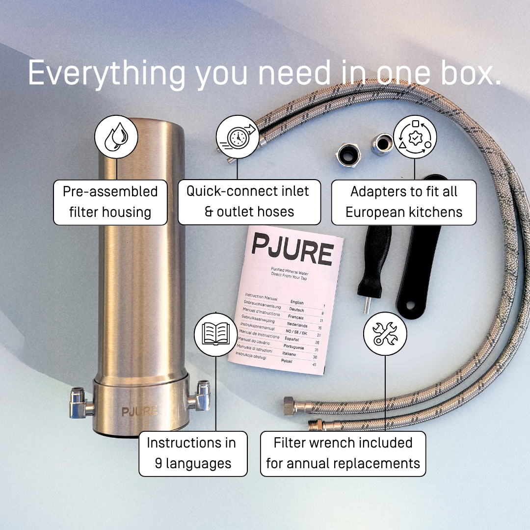 PJURE water filter box contents — pre-assembled stainless steel filter housing, quick-connect inlet and outlet hoses, EU adapters, filter wrench and instruction manual in 9 languages